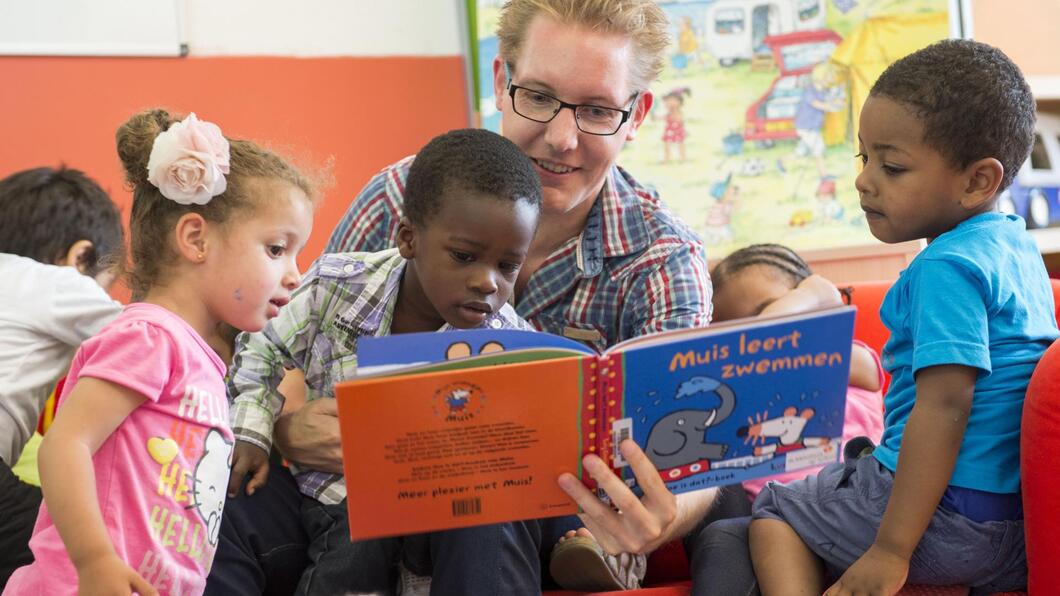 Docent leest groepje peuters voor uit kinderboek