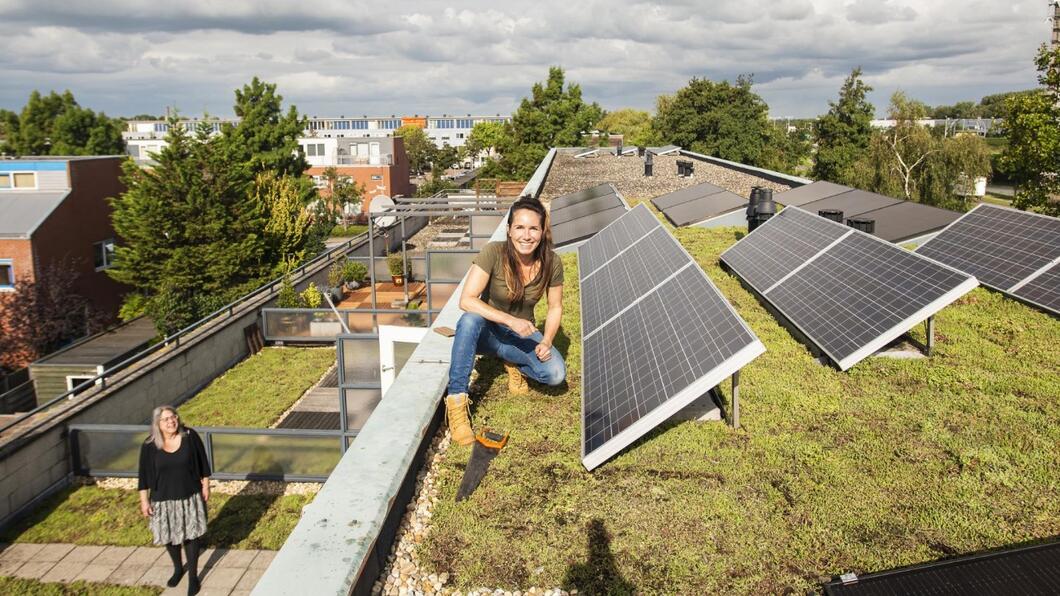 vrouw naast pas geïnstalleerde zonnepanelen op een dak