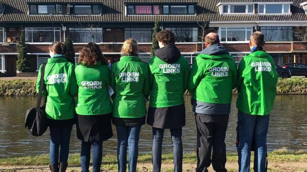 Groep van GroenLinks-leden staat met hun rug naar de camera met groene jasjes zichtbaar