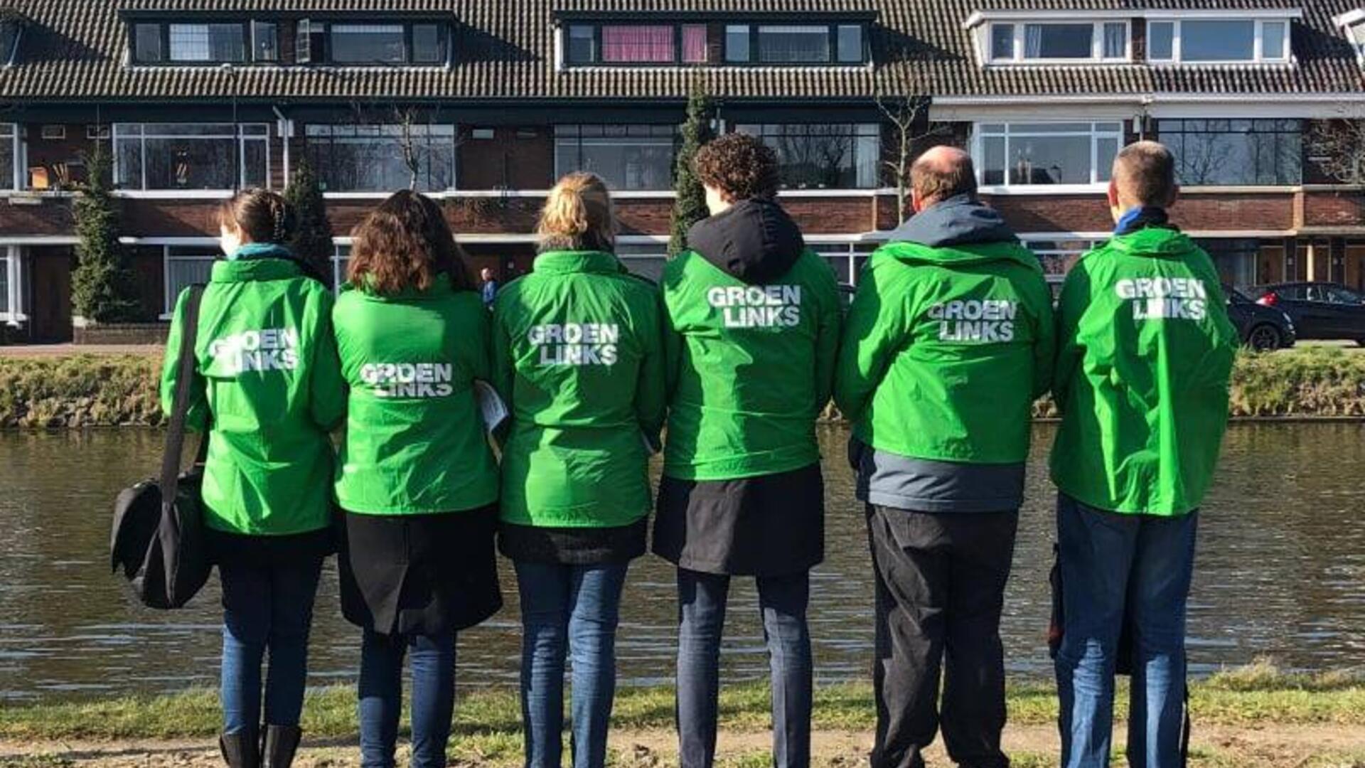 Groep van GroenLinks-leden staat met hun rug naar de camera met groene jasjes zichtbaar